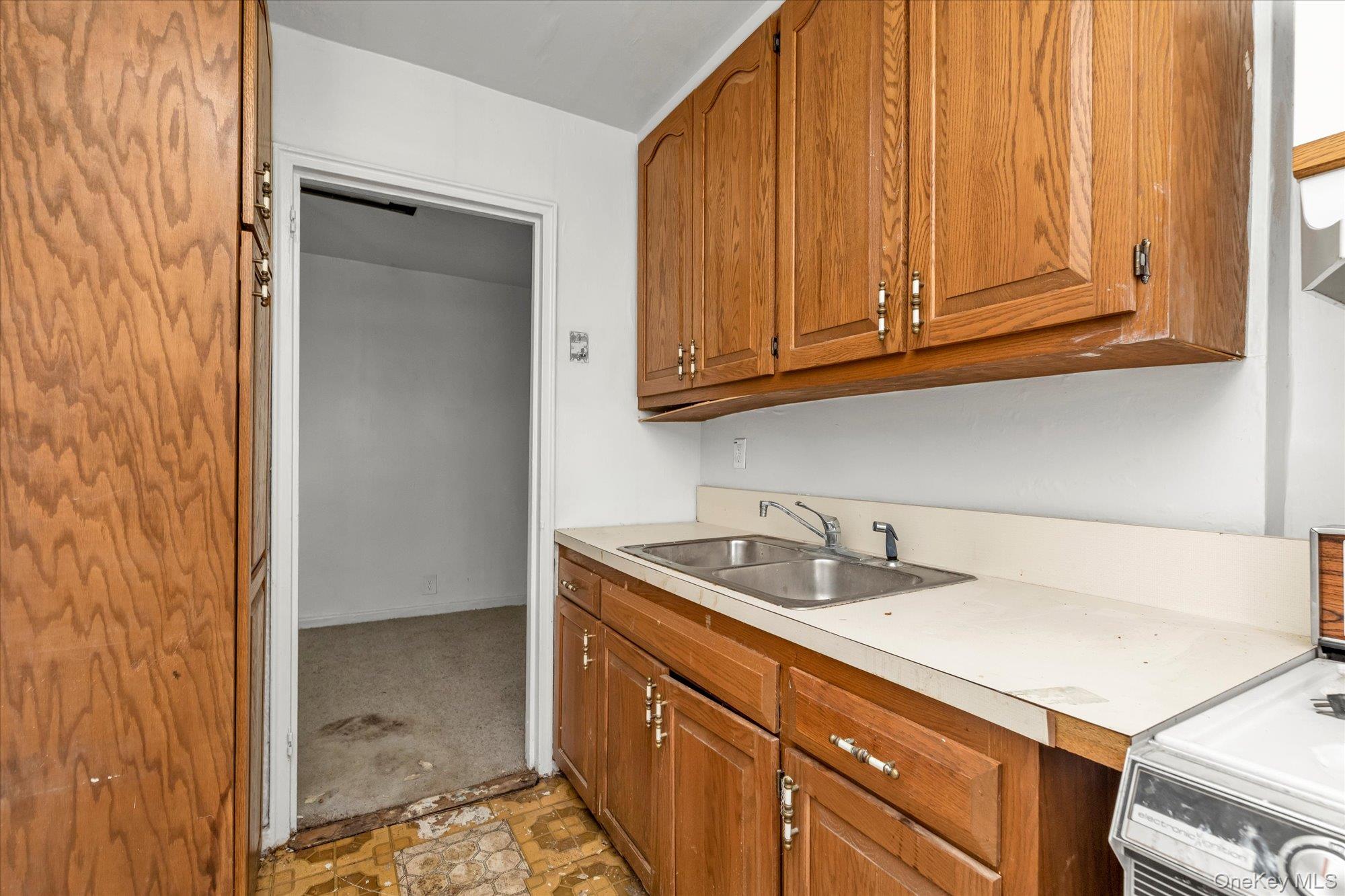 196-32 69th Avenue, Unit 1 Queens, NY 11365 - Photo 7 of 21 Kitchen with brown cabinetry, light countertops, range, and light colored carpet