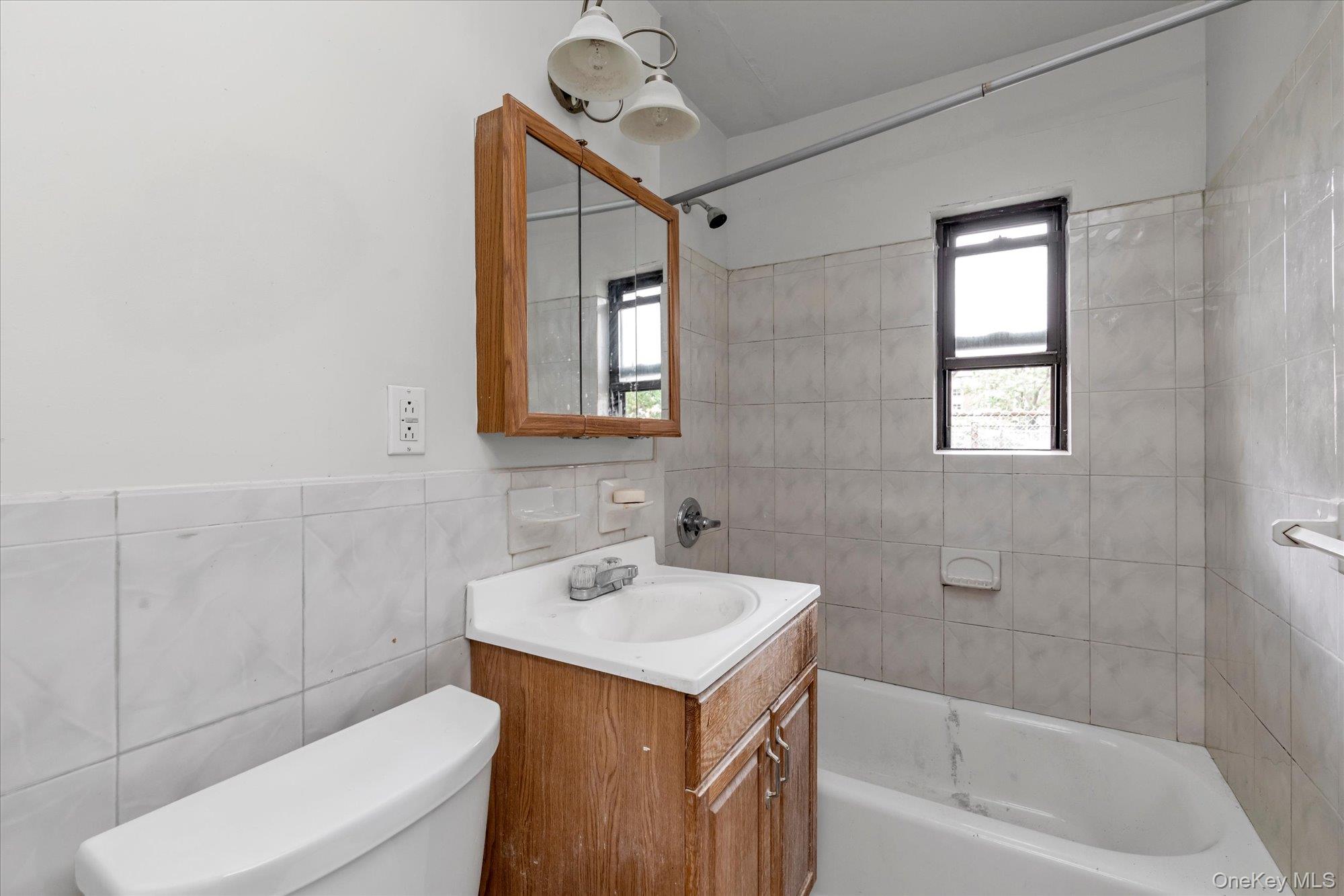 196-32 69th Avenue, Unit 1 Queens, NY 11365 - Photo 10 of 21 Full bathroom with vanity, tile walls, and shower / tub combination
