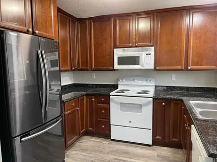 a kitchen with stainless steel appliances granite countertop a stove refrigerator and cabinets