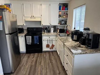a kitchen with granite countertop a refrigerator stove and sink