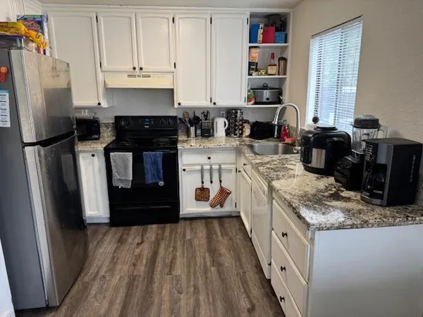 a kitchen with granite countertop a refrigerator stove and sink