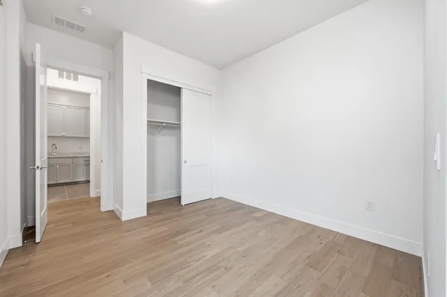 an empty room with wooden floor & bathroom