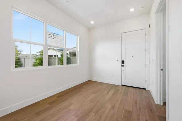 a view of an empty room with wooden floor and a window