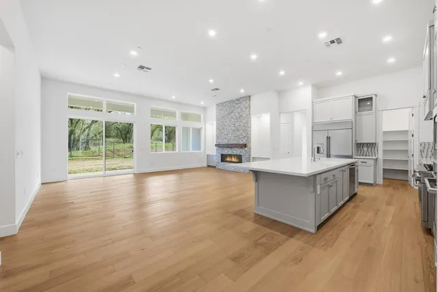 a large kitchen with stainless steel appliances granite countertop a large counter top and a wooden floors