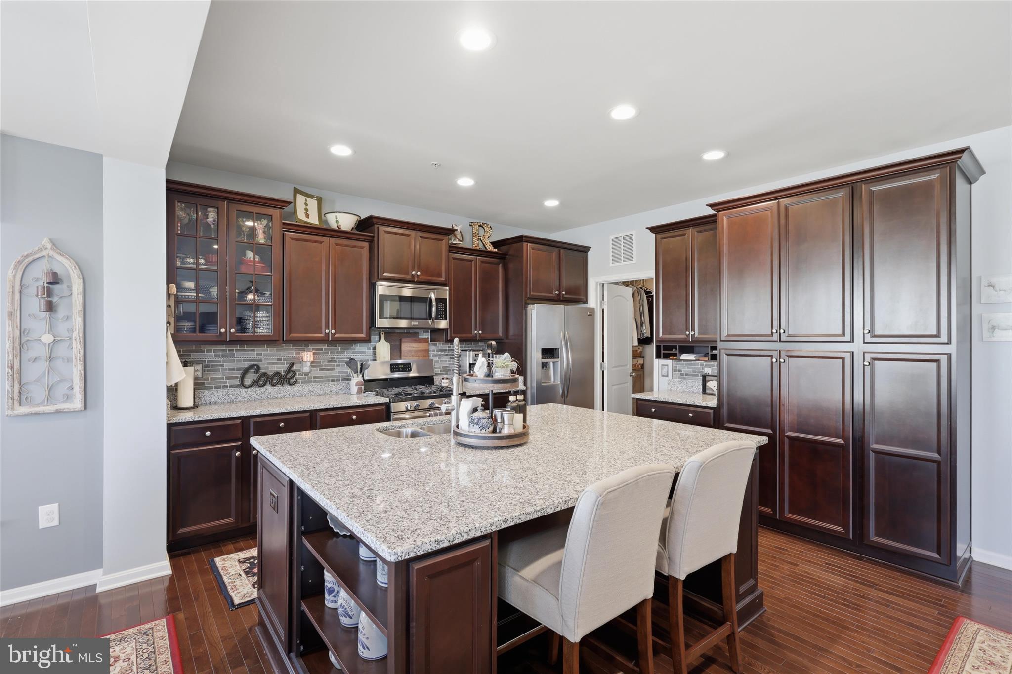 6606 Corbel Way Frederick, MD 21703 - Photo 5 of 60 a kitchen with stainless steel appliances granite countertop a kitchen island hardwood floor a dining table and chairs