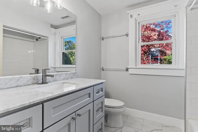 a bathroom with a granite countertop sink mirror vanity and toilet