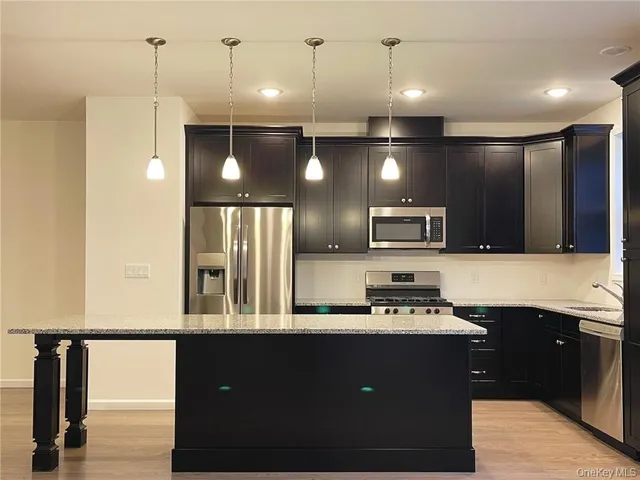 a kitchen with stainless steel appliances kitchen island granite countertop a sink a stove and a refrigerator