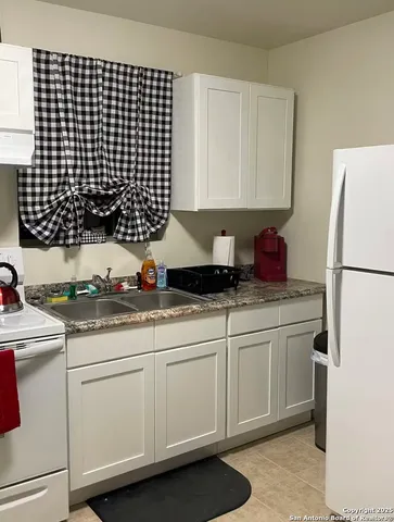 a kitchen with granite countertop a sink a stove a washer and dryer