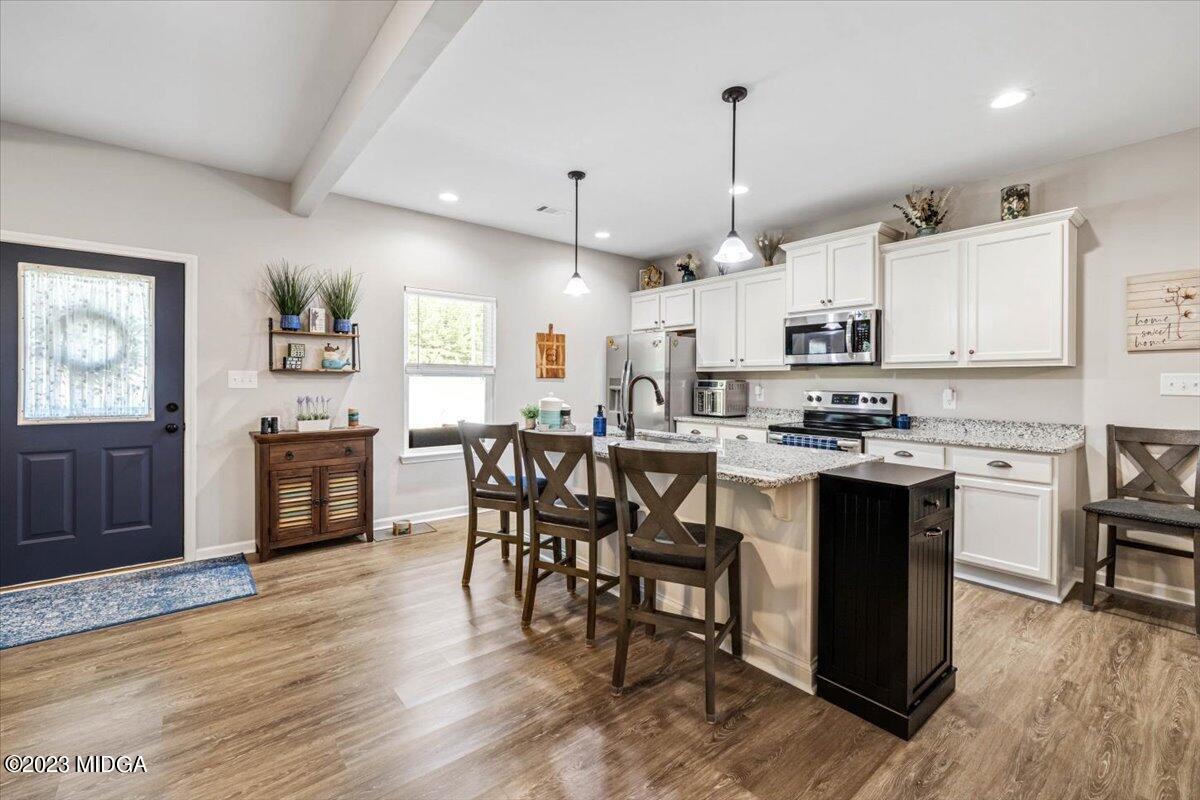 249 Davis Road Gray, GA 31032 - Photo 6 of 53 a kitchen with stainless steel appliances granite countertop a stove top oven a sink dishwasher and a dining table with wooden floor