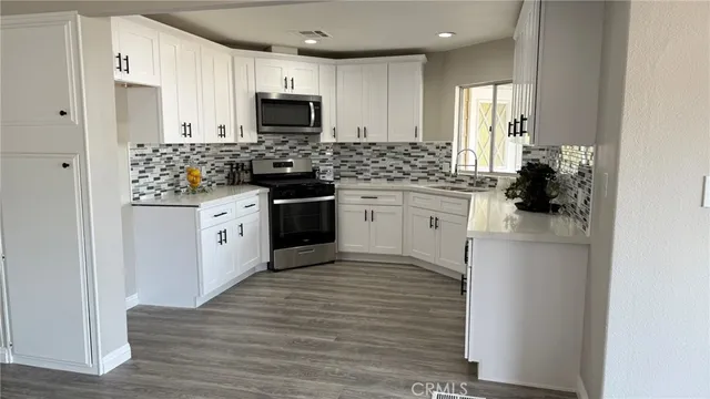 a kitchen with stainless steel appliances granite countertop a stove top oven a sink and a refrigerator