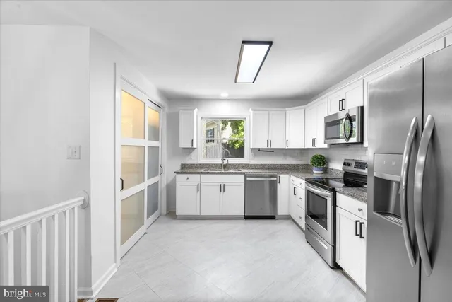 a kitchen with white cabinets and stainless steel appliances