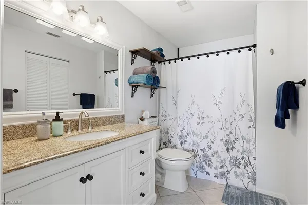 a bathroom with a granite countertop sink a toilet and shower