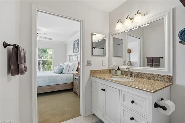 a en suite bathroom with a granite countertop sink and a mirror