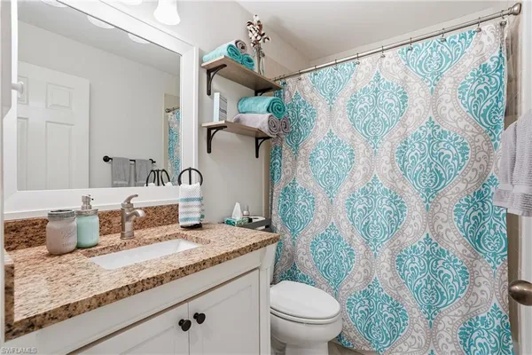 a bathroom with a granite countertop sink a toilet and a shower curtain