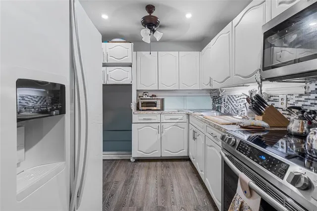 a kitchen with white cabinets and appliances