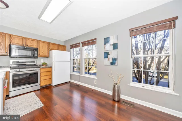 a kitchen with wooden floors and white stainless steel appliances