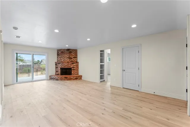 an empty room with wooden floor and a fireplace