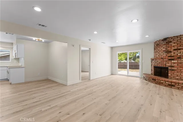 an empty room with wooden floor fireplace and windows