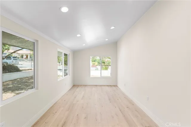 a view of an empty room with a window and wooden floor