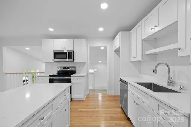 a view of a kitchen with a sink and dishwasher a refrigerator with wooden floor