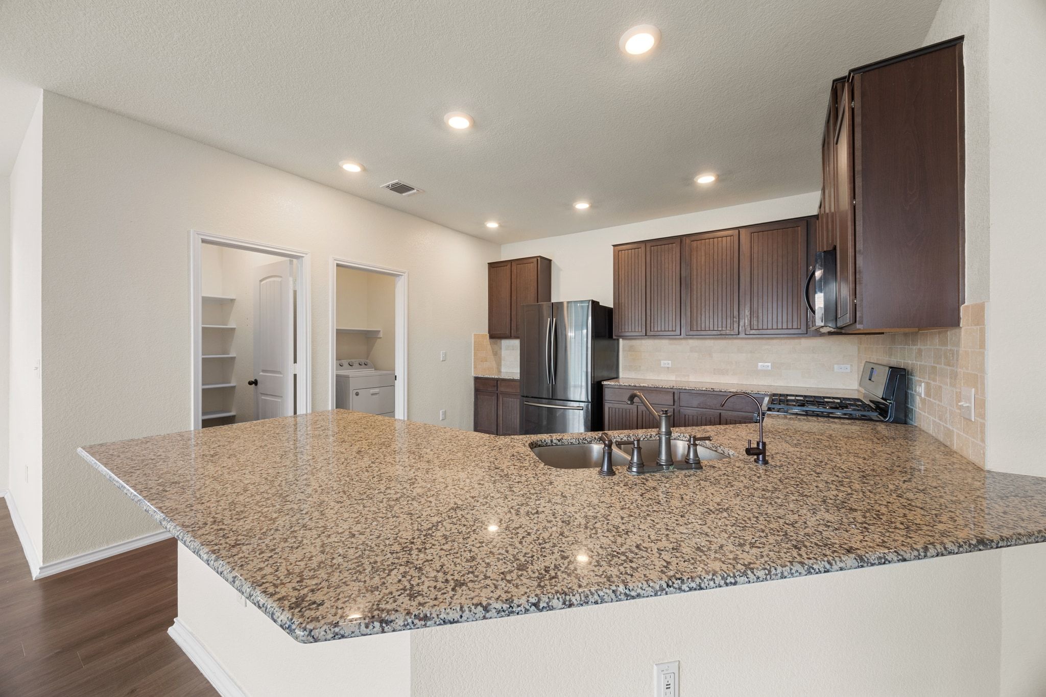 136 Vickers Street Georgetown, TX 78628 - Photo 10 of 33 a kitchen with stainless steel appliances granite countertop a sink refrigerator and cabinets