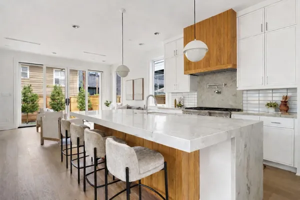 a kitchen with stainless steel appliances granite countertop a stove a sink a dining table and chairs with wooden floor