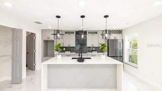 a kitchen with stainless steel appliances kitchen island granite countertop a sink and white cabinets