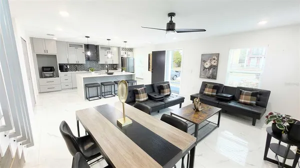 a living room with stainless steel appliances furniture a rug and a kitchen view