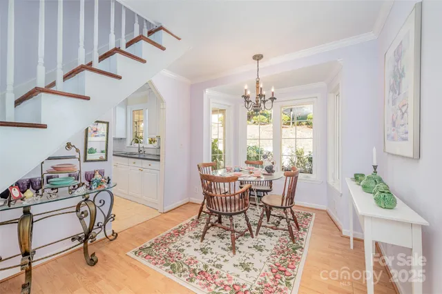 a dining room with wooden floor a chandelier a wooden table and chairs