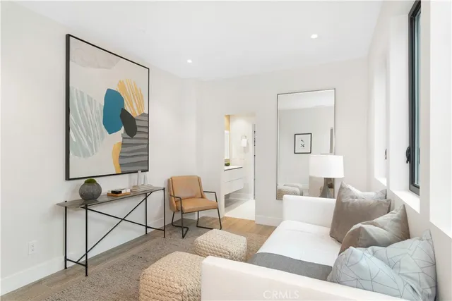 a bedroom with a large bed couch and two windows