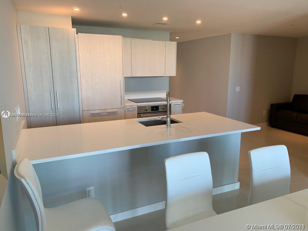 a workspace with stainless steel appliances white cabinets a table and chairs