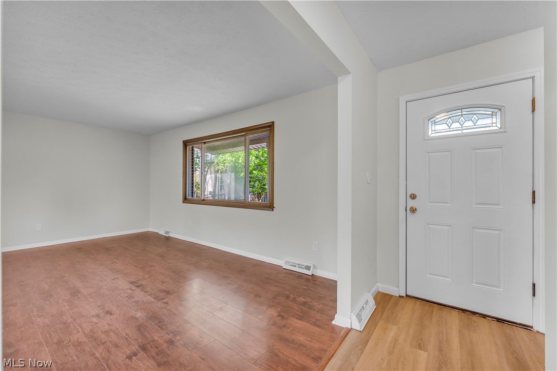 2540 Charney Road University Heights, OH 44118 - Photo 4 of 44 Entry foyer featuring a white paneled door with an arched leaded glass insert, warm wood-finish flooring, and white walls