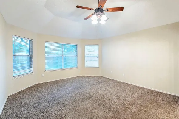 an empty room with windows and fan