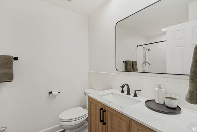 9706 Raintree Drive Sandy, UT 84092 - Photo 15 of 42 White subway tile backsplash, wood-finish vanity with black hardware, white countertop with integrated sink, and black-framed rectangular mirror