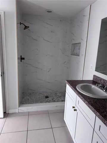 a bathroom with a granite countertop sink a mirror and shower