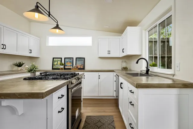 a kitchen with granite countertop a sink stove and cabinets