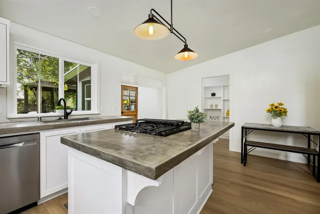 a kitchen with a stove a counter space and wooden floor