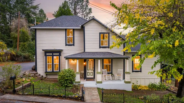 a front view of a house with glass windows and plants