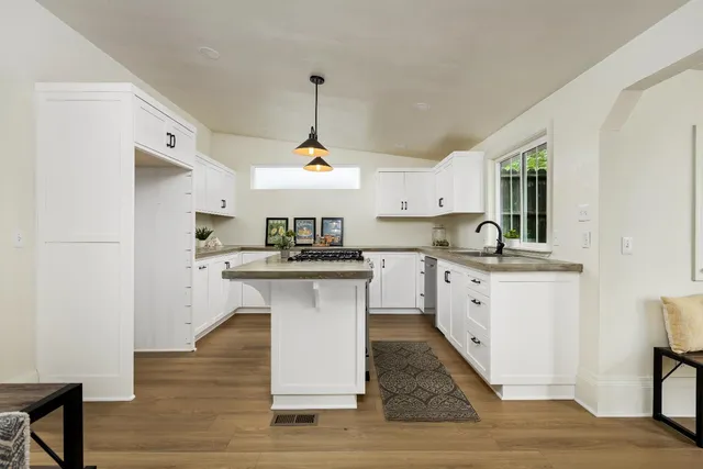 a kitchen with kitchen island granite countertop a sink a counter space and stainless steel appliances