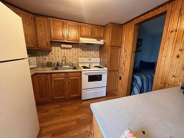2377 Finn Road Babbitt, MN 55706 - Photo 5 of 32 Kitchen featuring white appliances, a sink, under cabinet range hood, light wood-type flooring, and brown cabinetry