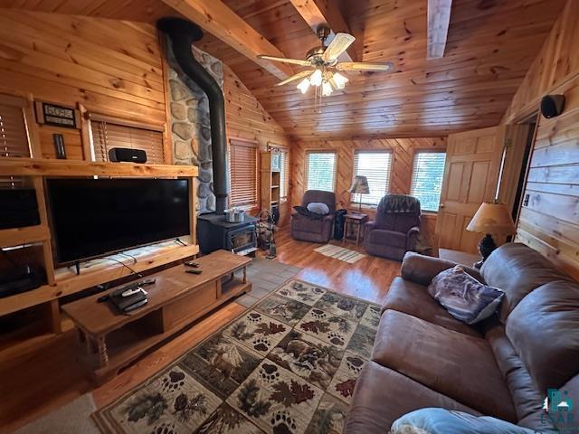 2377 Finn Road Babbitt, MN 55706 - Photo 8 of 32 Living room featuring a wood stove, wooden ceiling, wooden walls, wood finished floors, and a ceiling fan
