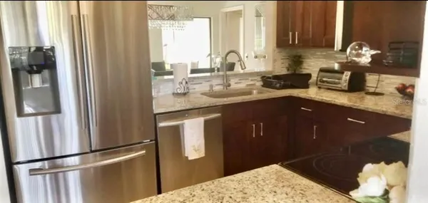 a kitchen with stainless steel appliances granite countertop a refrigerator a sink and a stove