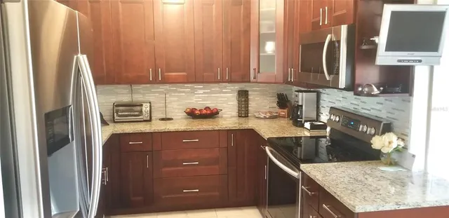 a kitchen with stainless steel appliances granite countertop a refrigerator a stove and a sink with wooden floor