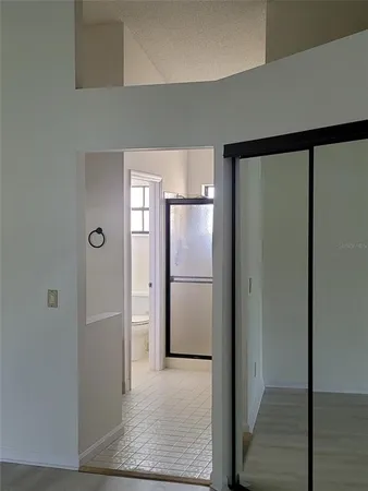 a view of a refrigerator in kitchen and an empty room with wooden floor
