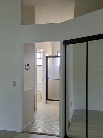 a view of a refrigerator in kitchen and an empty room with wooden floor