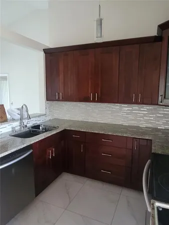 a kitchen with granite countertop wooden cabinets and sink