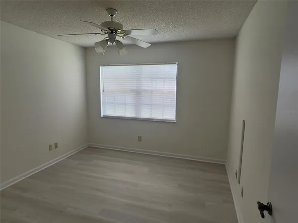 an empty room with a window and a fan