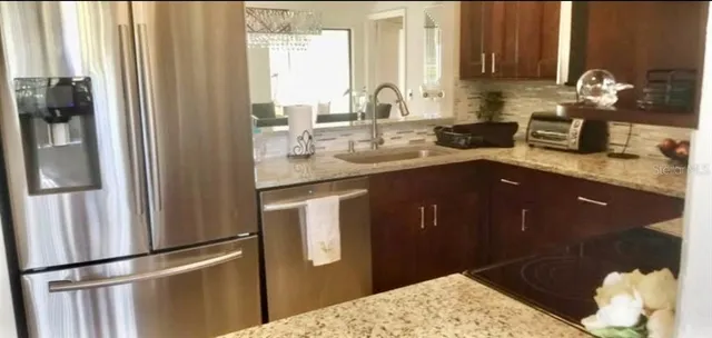 a kitchen with stainless steel appliances granite countertop a refrigerator a sink and a stove