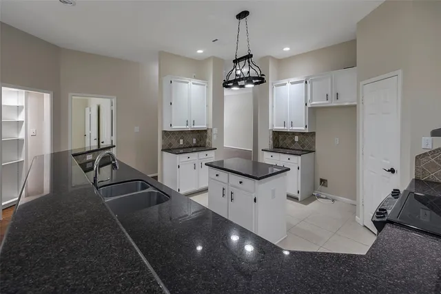 a kitchen with granite countertop a stove a sink and a refrigerator