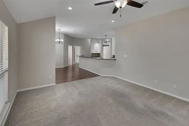 an empty room with chandelier fan and windows
